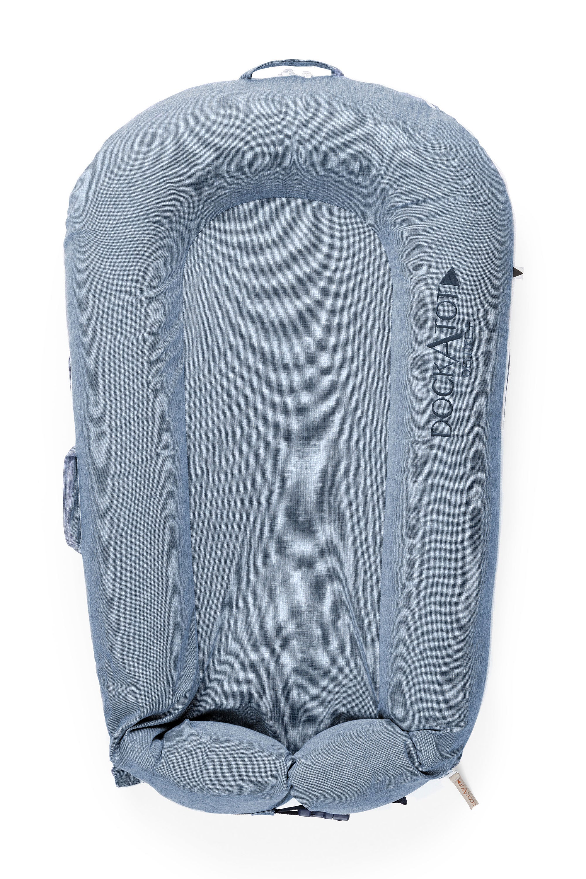 A blue DockATot LAST CHANCE: Deluxe+ Dock - Indigo Chambray baby lounger isolated on a white background. The lounger has a cushioned, oval shape with side handles and prominently displays the &quot;DockATot&quot; logo.